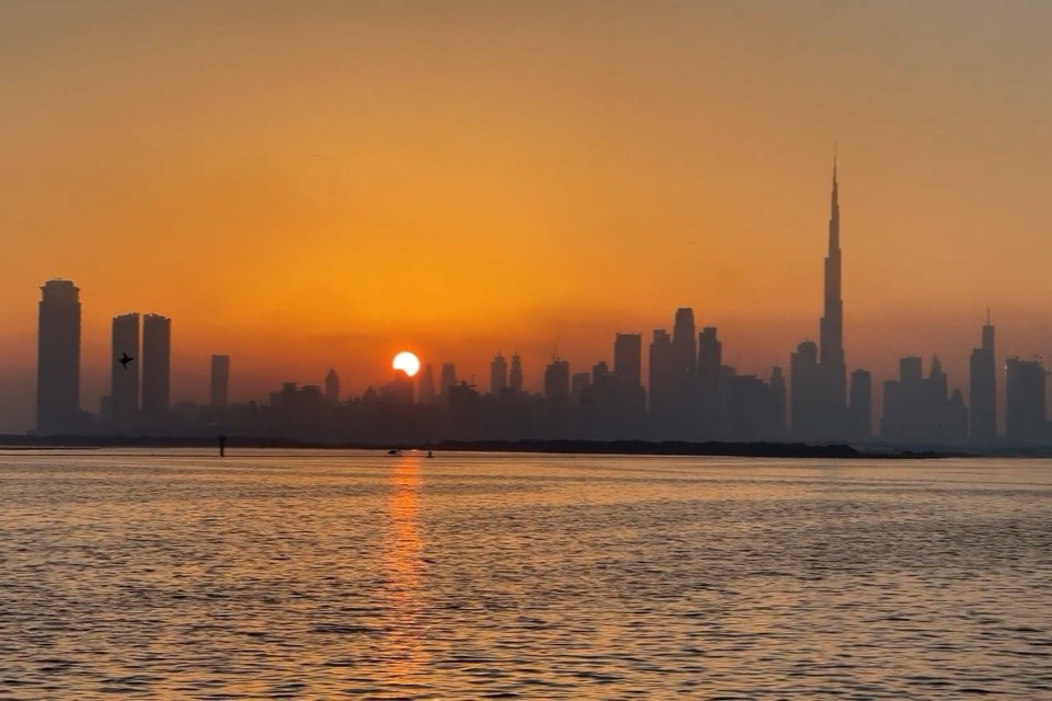 The Dubai skyline and the Burj Khalifa at sunset, across the water